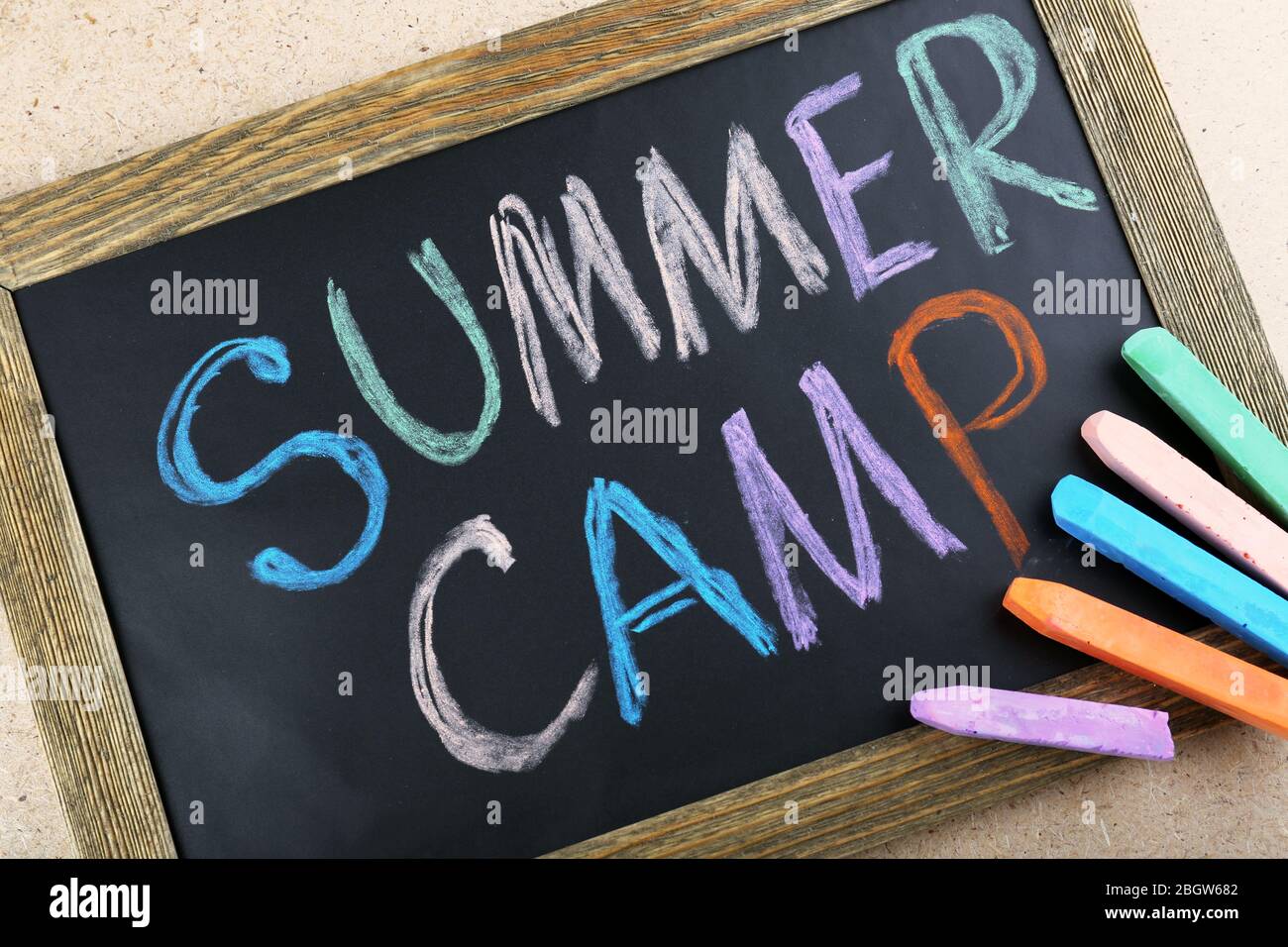 Texte Camp d'été écrit avec craie sur tableau de surveillance, et quelques bâtons de craie de différentes couleurs Banque D'Images