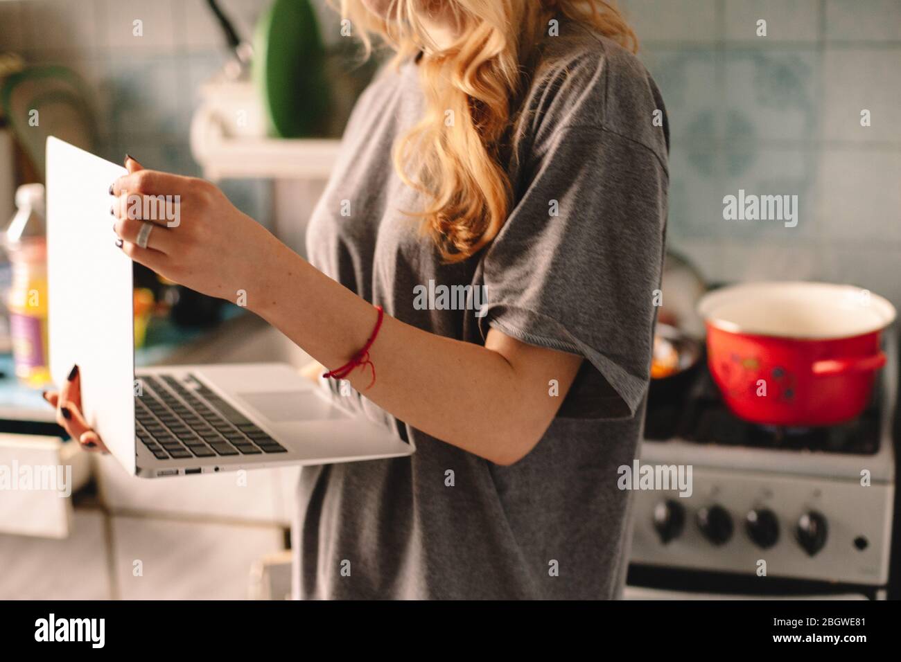 Femme utilisant un ordinateur portable pendant la cuisson des aliments dans la cuisine Banque D'Images