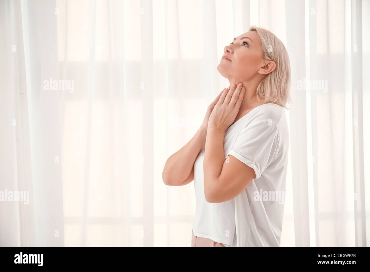 Femme avec problème de glande thyroïde à la maison Banque D'Images