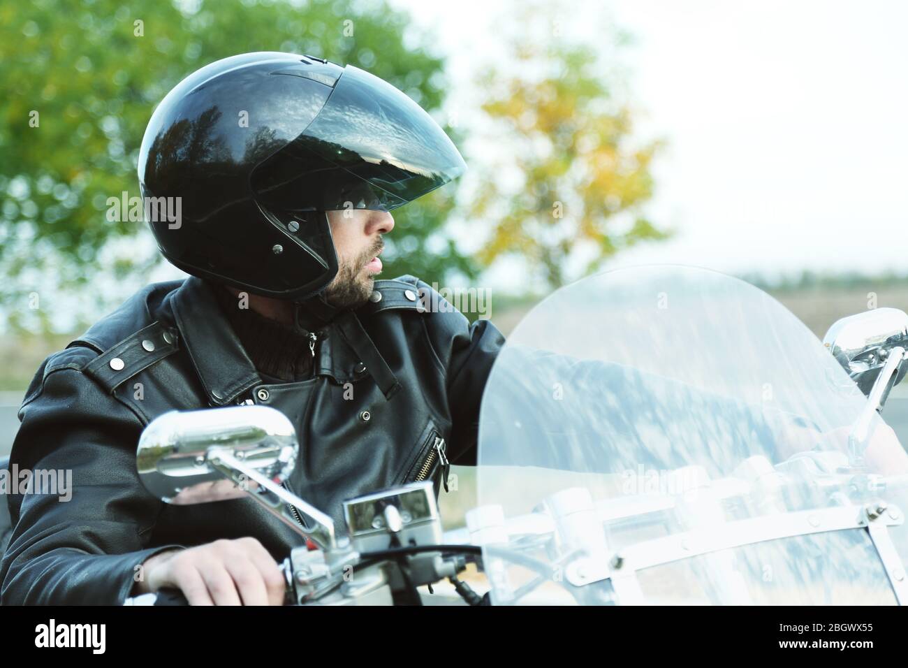 Le Biker homme en casque noir est assis sur le vélo Banque D'Images