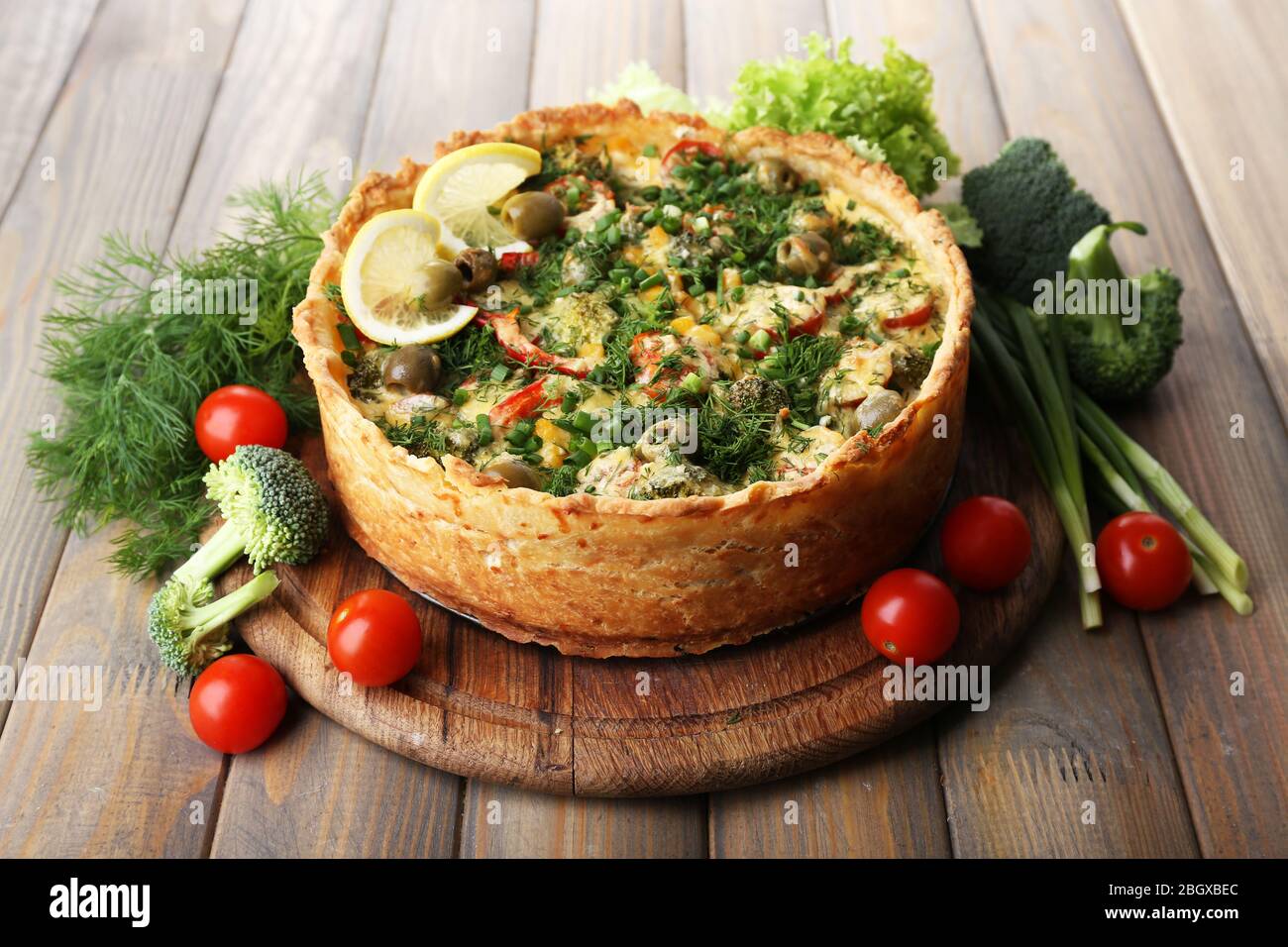 Tarte aux légumes avec brocoli, pois, tomates et fromage sur fond de bois Banque D'Images