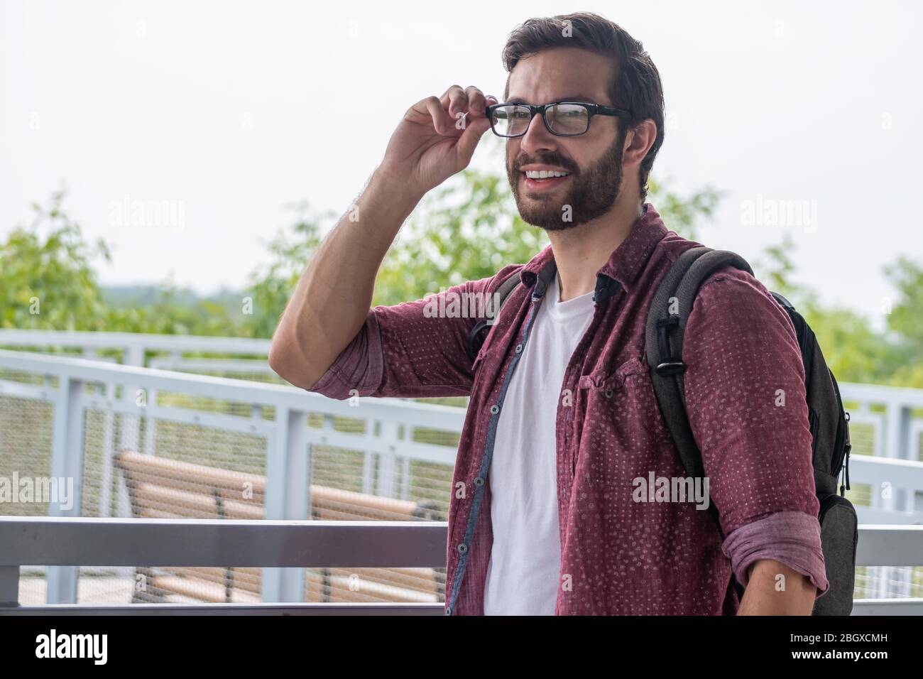 Un homme hipster barbu portant un bouton rouge en bas chemise portant ses  lunettes prescrites pour voir plus clairement ce qui est à la distance avec  une stare droite Photo Stock -