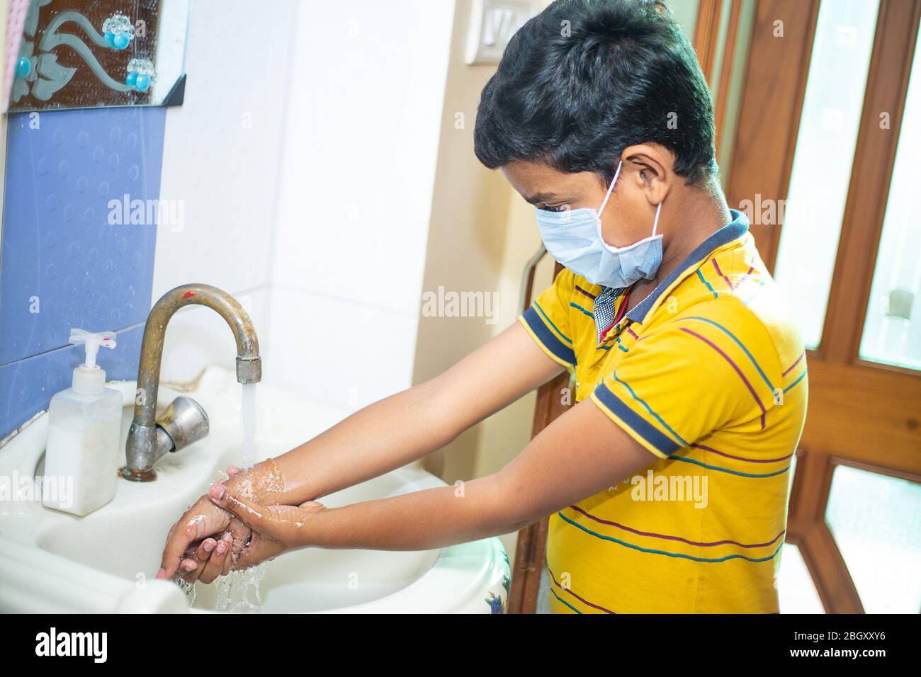 Masque de port pour enfants laver les mains avec du savon et de l'eau dans  l'évier de salle de bains à la maison, hygiène des mains de nettoyage pour  la prévention des