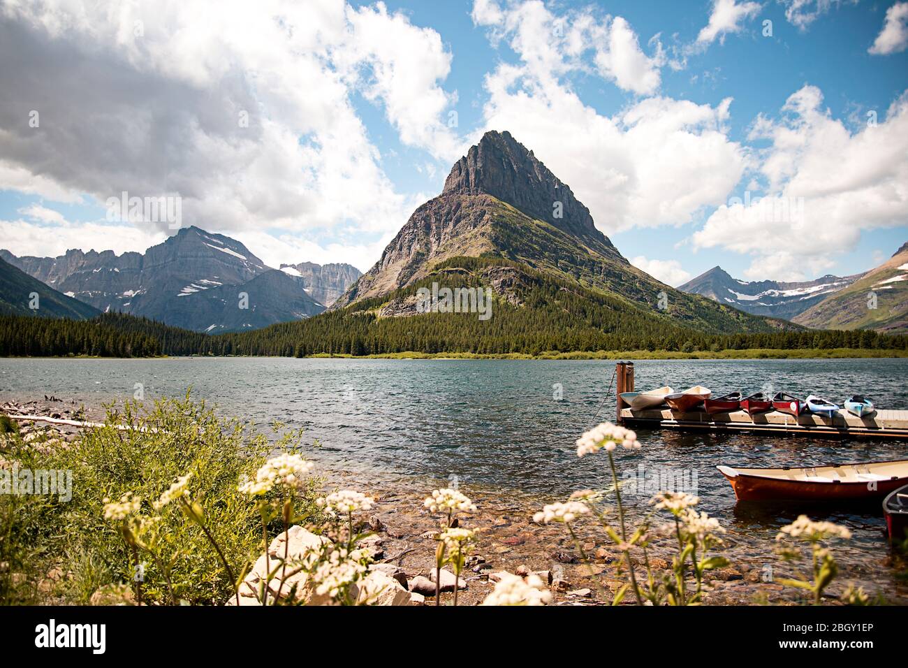 Paysage de montagne de Grinnell point et du lac Swiftcurrent dans le parc national des Glaciers. Des bateaux amarrés dans l'eau avec un ciel bleu animé abov Banque D'Images