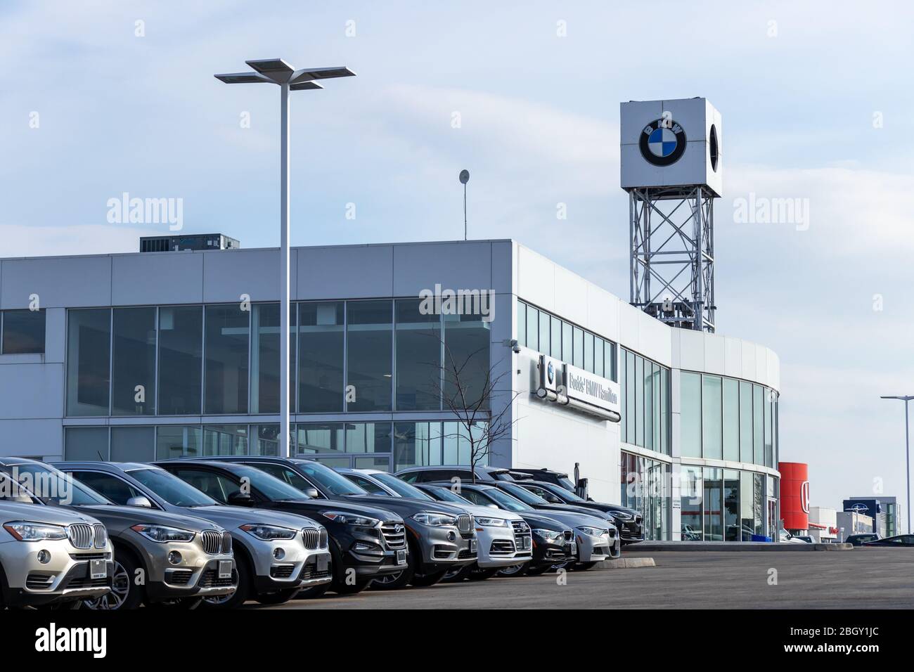 Concessionnaire BMW vu en arrière-plan, avec des voitures stationnées sur le côté. Banque D'Images