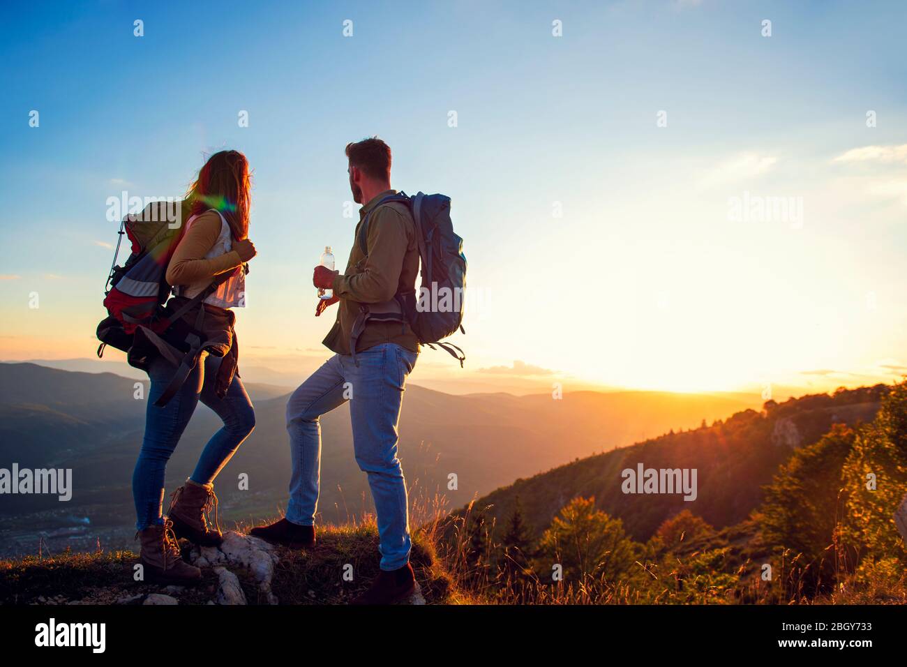 Les jeunes couples qui ont fait de la randonnée sur le pic de l'eau potable de montagne Banque D'Images