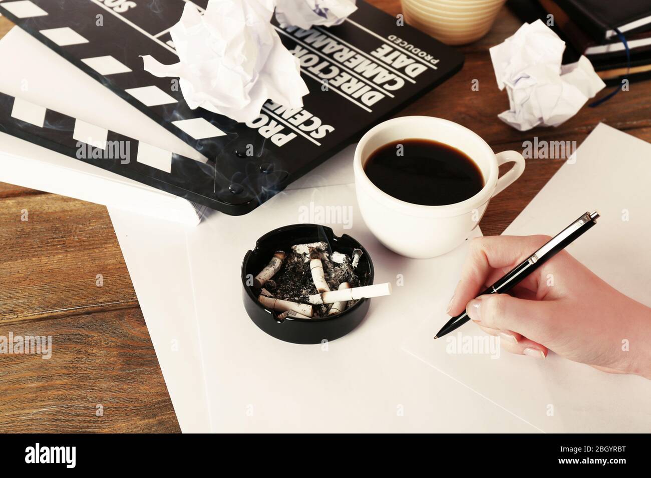 Main féminine avec tasse de café, clapper mobile et feuilles de papier sur fond en bois Banque D'Images