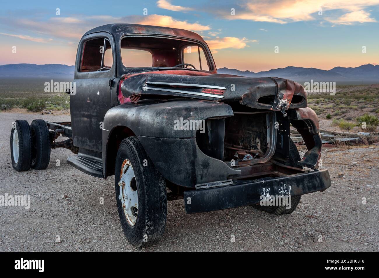 Un pick-up noir naufragé et rouillé dans la ville fantôme de Rhyolite, dans la vallée de la mort, au coucher du soleil Banque D'Images