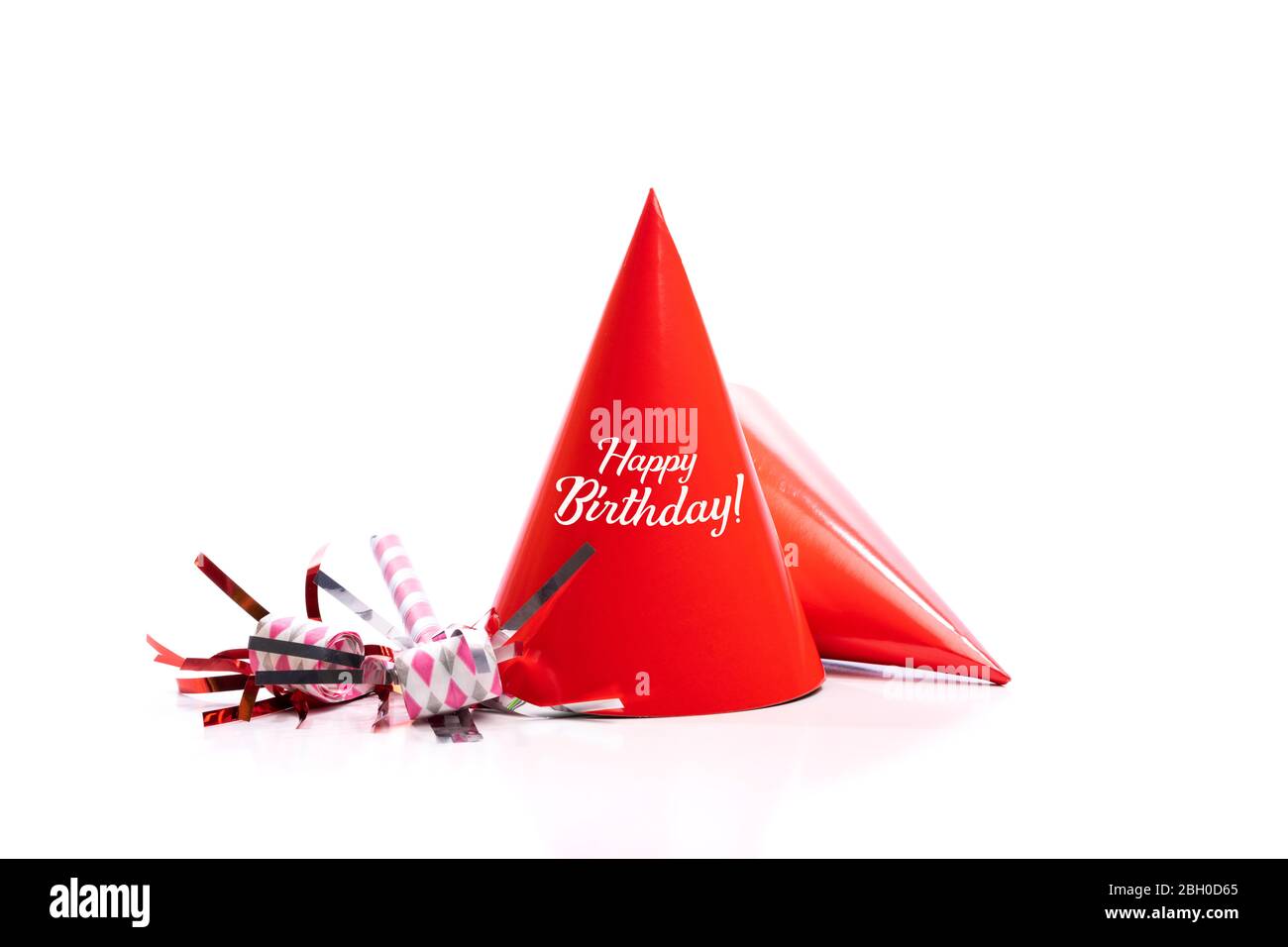 Chapeaux d'anniversaire rouges et appareils de bruit sur fond blanc. Banque D'Images