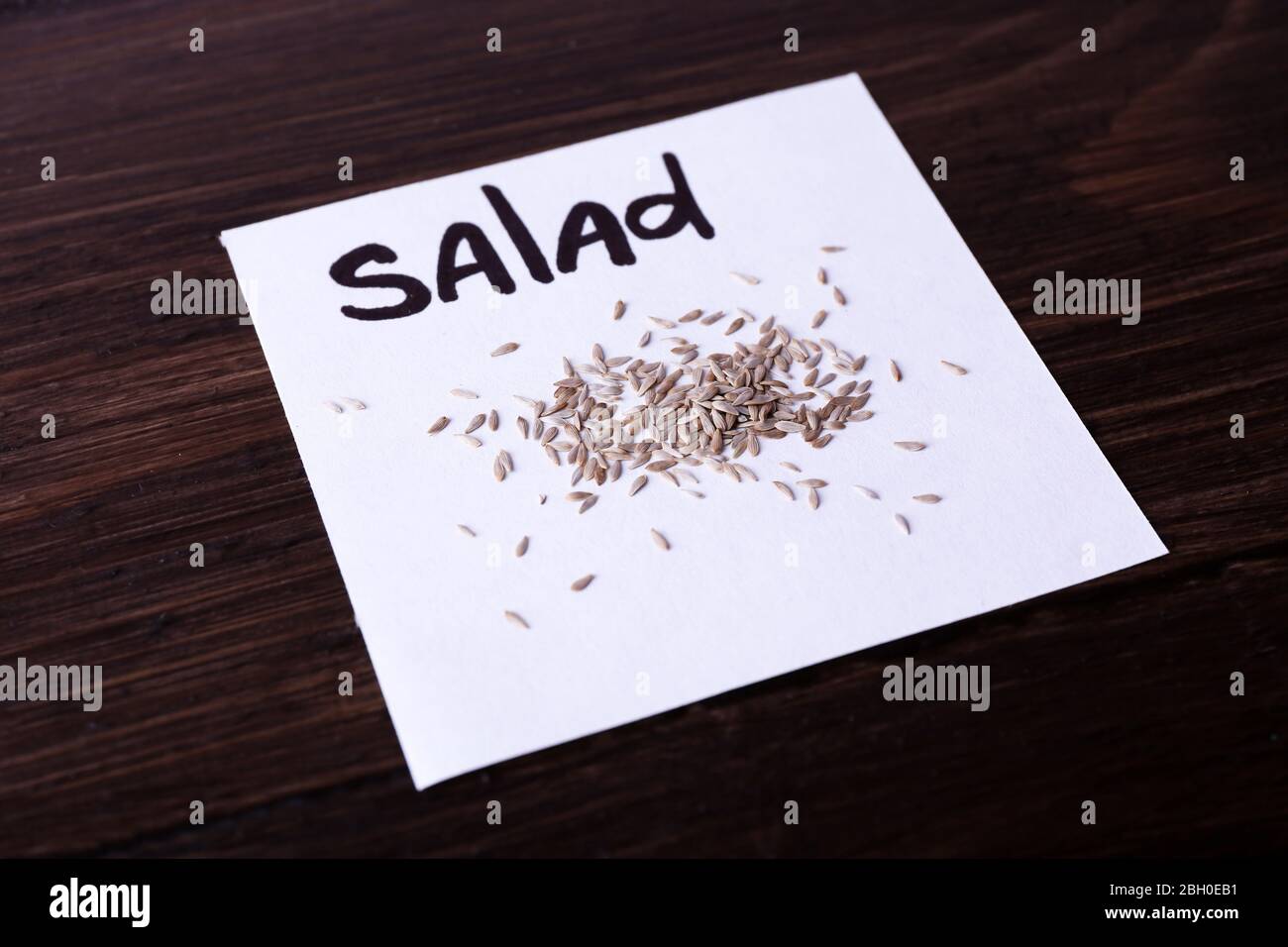 Salade de graines sur un morceau de papier sur fond de bois Banque D'Images