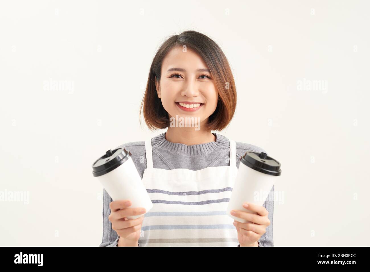 Portrait de gentille sympathique fille agréable donnant deux grand Latte isolé sur fond gris copie-espace Banque D'Images