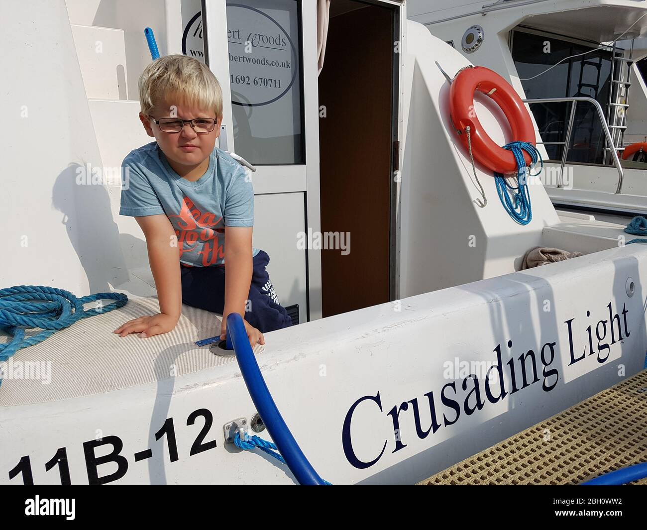 Un jeune garçon remplit l'eau sur un bateau de vacances Norfolk broads amarré à Wroxham Banque D'Images