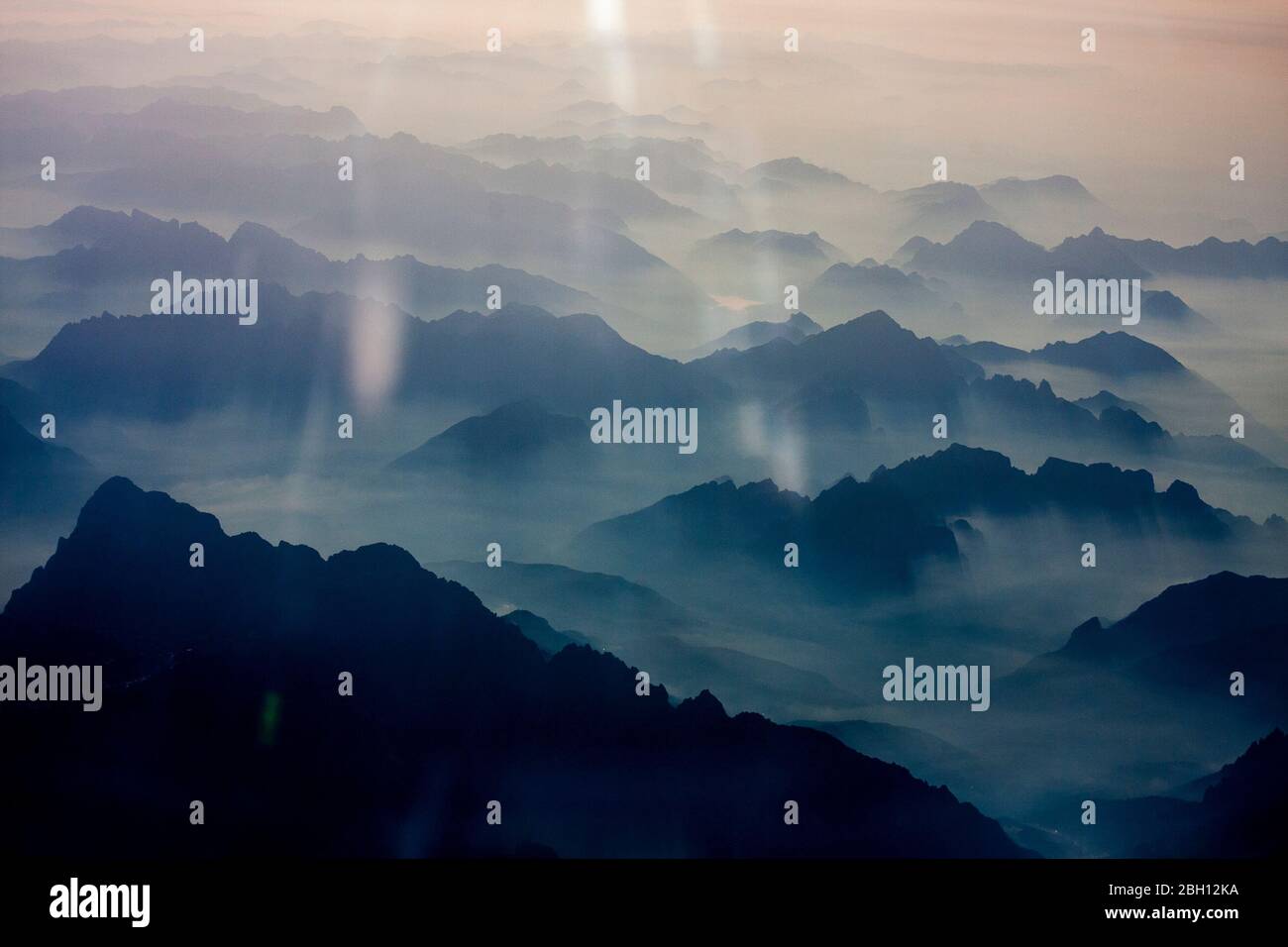Les sommets de montagne silhouettés des Alpes européennes sortent des nuages et du brouillard, comme on le voit dans un avion Banque D'Images
