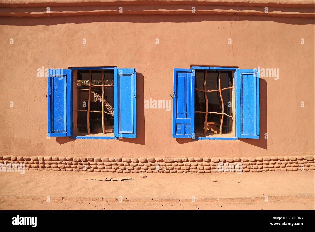 Fenêtres aux couleurs vives bleues sur la façade marron d'adobe au soleil, dans le nord du Chili Banque D'Images