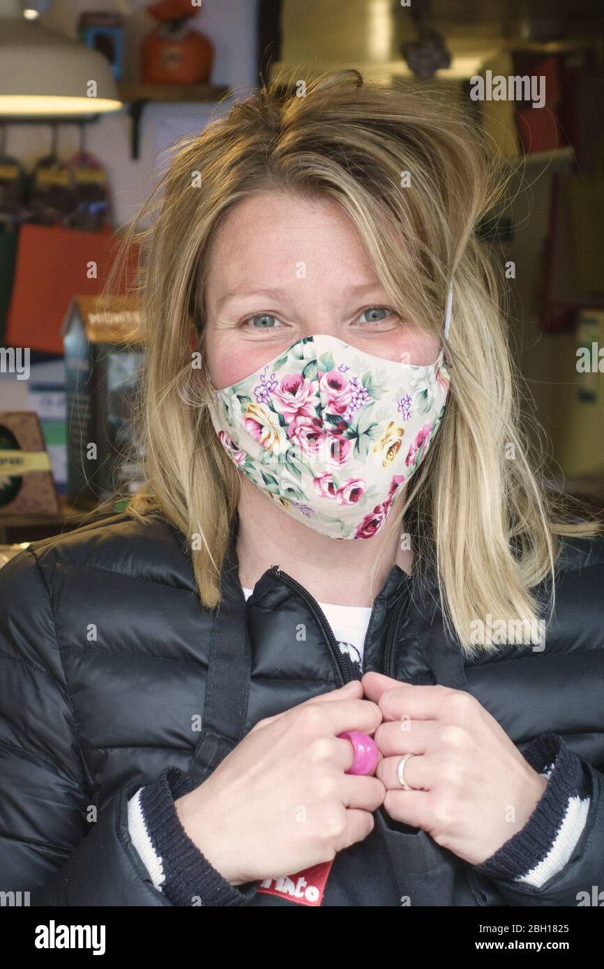 Leila Basletic porte un masque floral fabriqué à la main tout en servant des clients dans le déli de la ville à Presteigne, Powys, pays de Galles, Royaume-Uni Banque D'Images