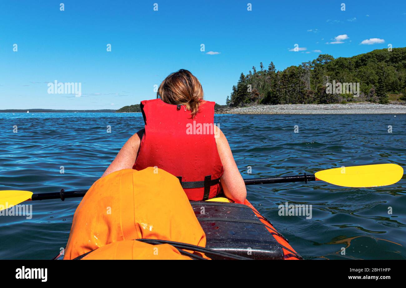 Gros plan sur le kayak féminin dans la baie de frenchmans Bay Bar Harbour Maine de la passanger derrière elle avec l'une des îles de porc-épic en arrière-plan. Banque D'Images
