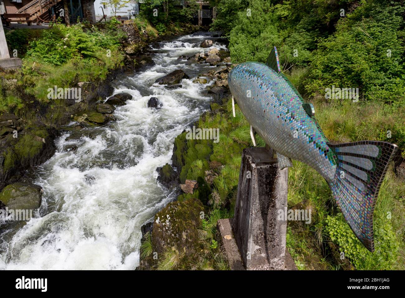 Statue de saumon géant surplombant une rivière à écoulement rapide Banque D'Images