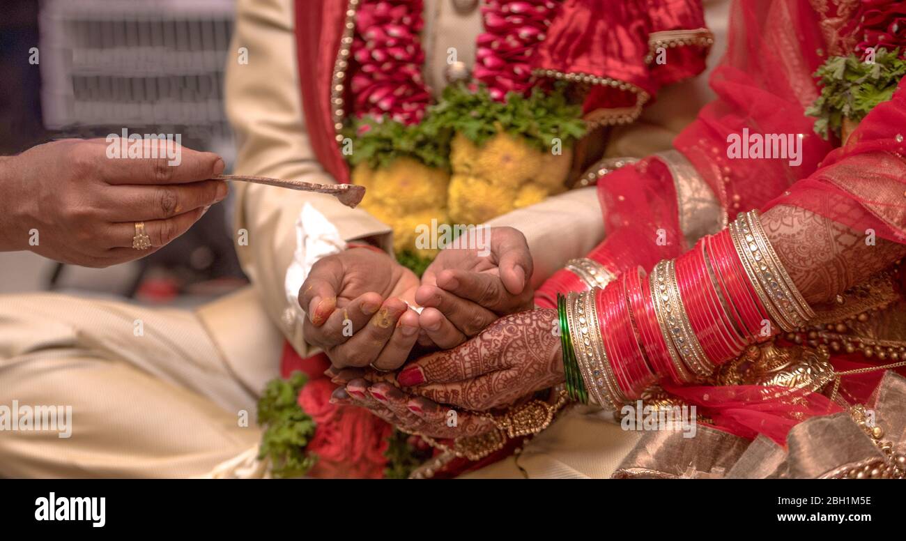 Scène traditionnelle de mariage indienne où un beau couple participe aux rituels hindous de leur cérémonie de mariage. Couple reçoit de l'eau Sainte. Banque D'Images
