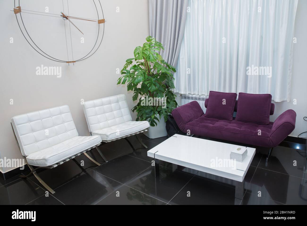 Canapé violet et fauteuil blanc. Horloges en fer et en bois . Design  intérieur . Rideau inférieur et blanc . Entrée au salon de beauté . Salle d' attente Photo Stock - Alamy
