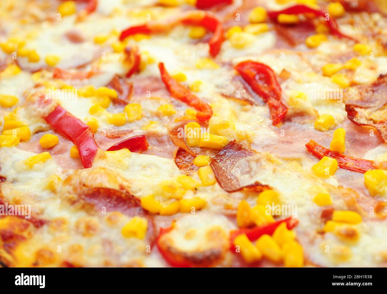 Une surface de pizza de plus près avec du jambon, du salami, du fromage et du poivre rouge. Photo de fond plein format de pizza, sélective concentrée au premier plan. Banque D'Images