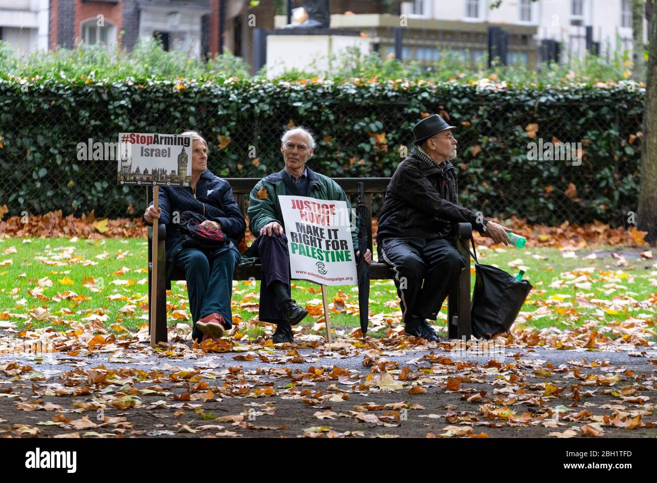 Les personnes âgées avec des signes de protestation assis sur un banc de parc à la Marche nationale et Rallye 'Justice Now: Faites-le juste pour la Palestine', Londres, 2017 Banque D'Images