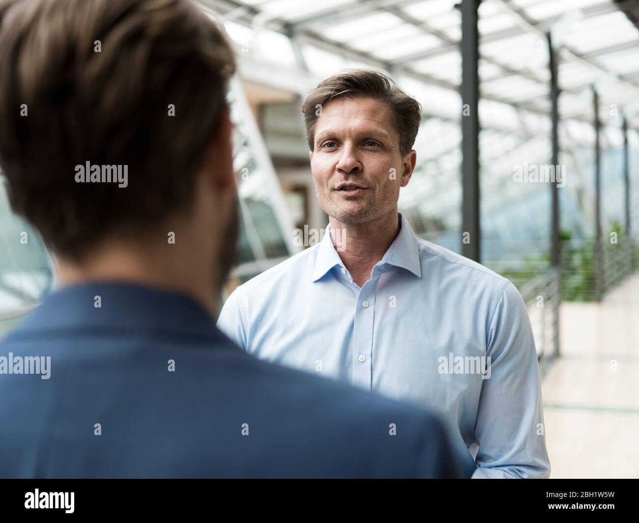 Homme d'affaires parlant à un collègue dans l'atrium du bâtiment de bureau Banque D'Images