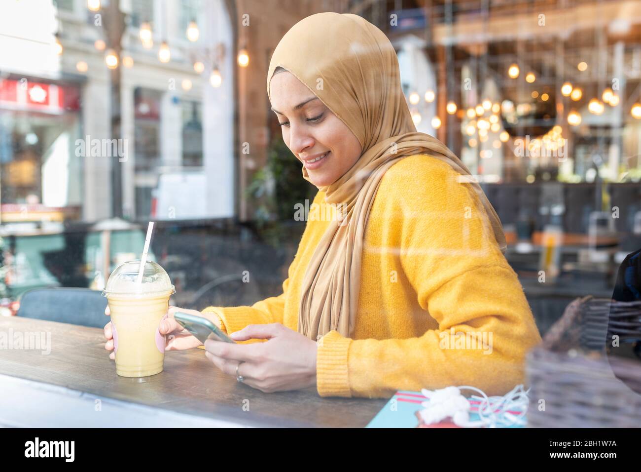 Portrait d'une jeune femme avec smoothie et smartphone dans un café Banque D'Images