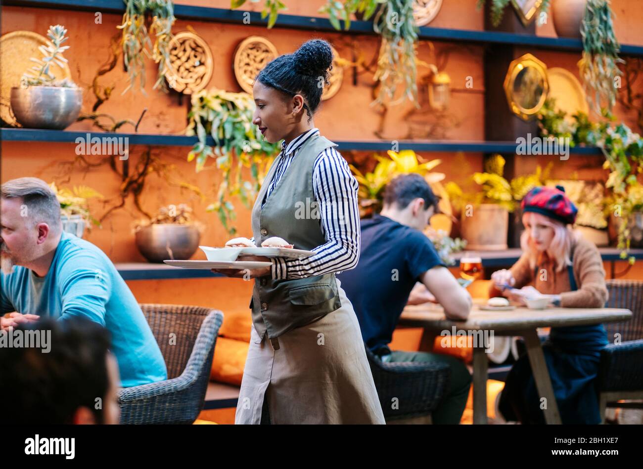 Les gens sont assis au restaurant, tandis que la serveuse sert de la nourriture Banque D'Images