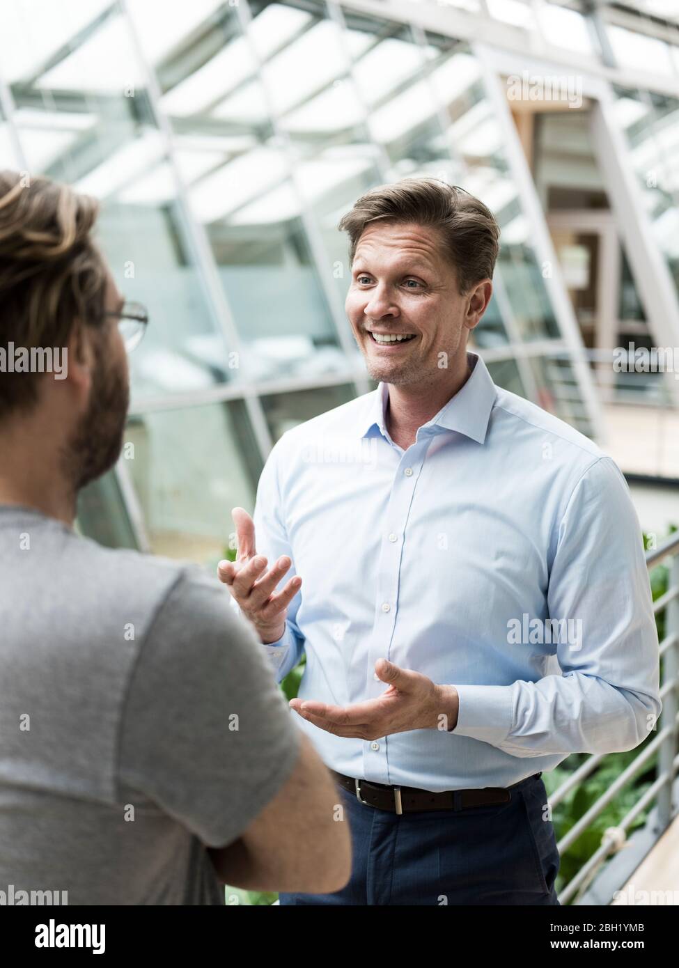 Homme d'affaires parlant à un collègue dans l'atrium du bâtiment de bureau Banque D'Images