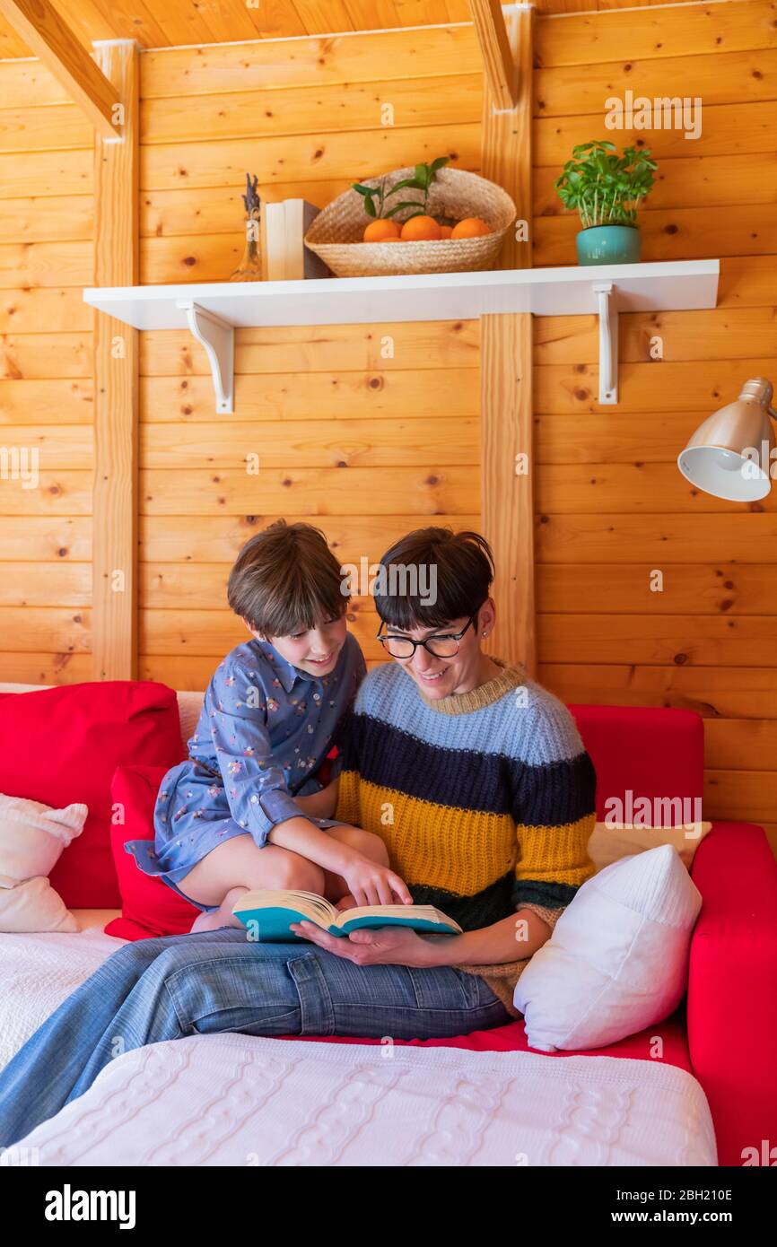 Mère et fille lisant un livre sur un canapé dans une cabine en bois Banque D'Images