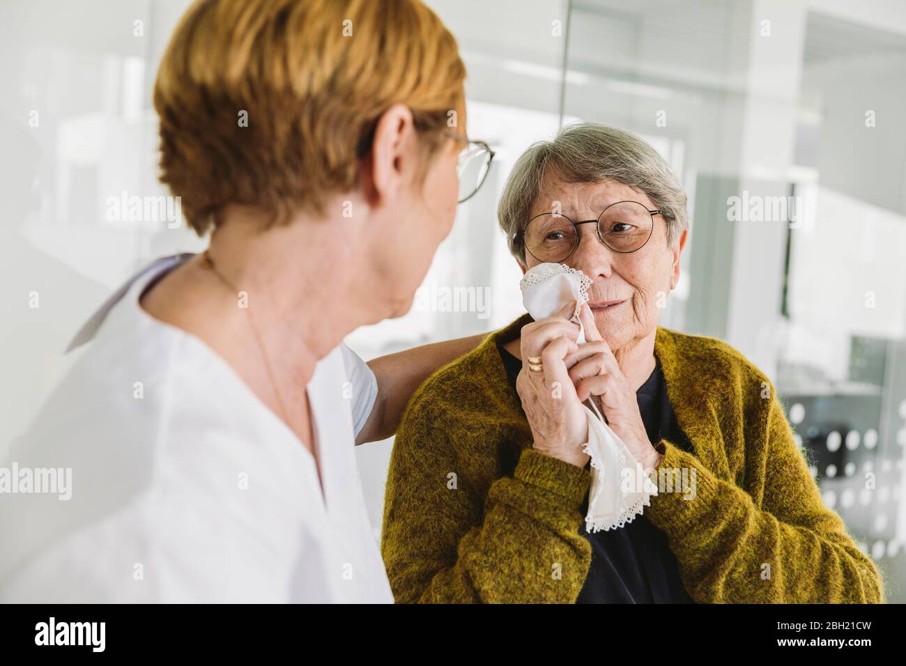 Assistant du médecin réconfortant un patient âgé triste en pratique médicale Banque D'Images