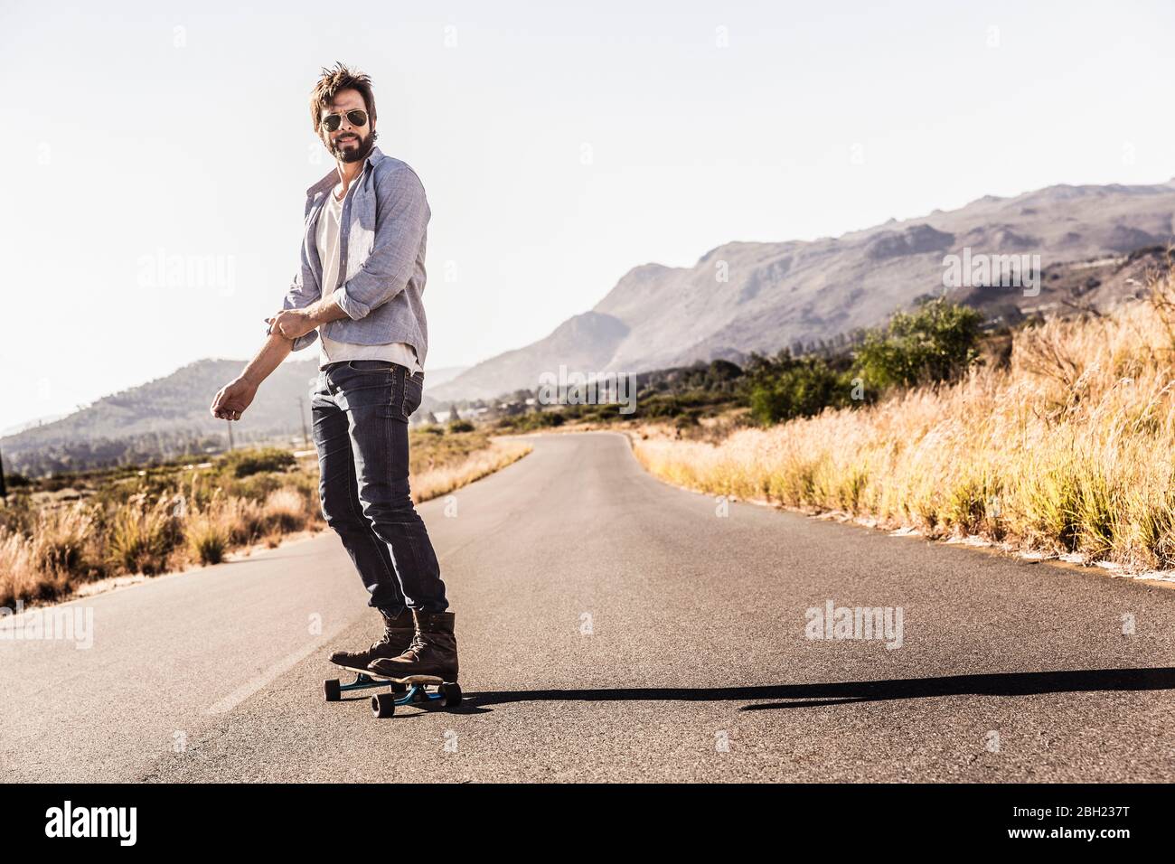 Homme à skate sur la route de campagne Banque D'Images