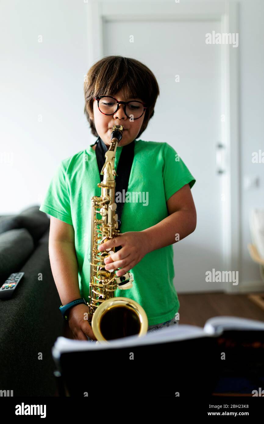 Garçon s'exerçant pour jouer le saxophone à la maison Banque D'Images