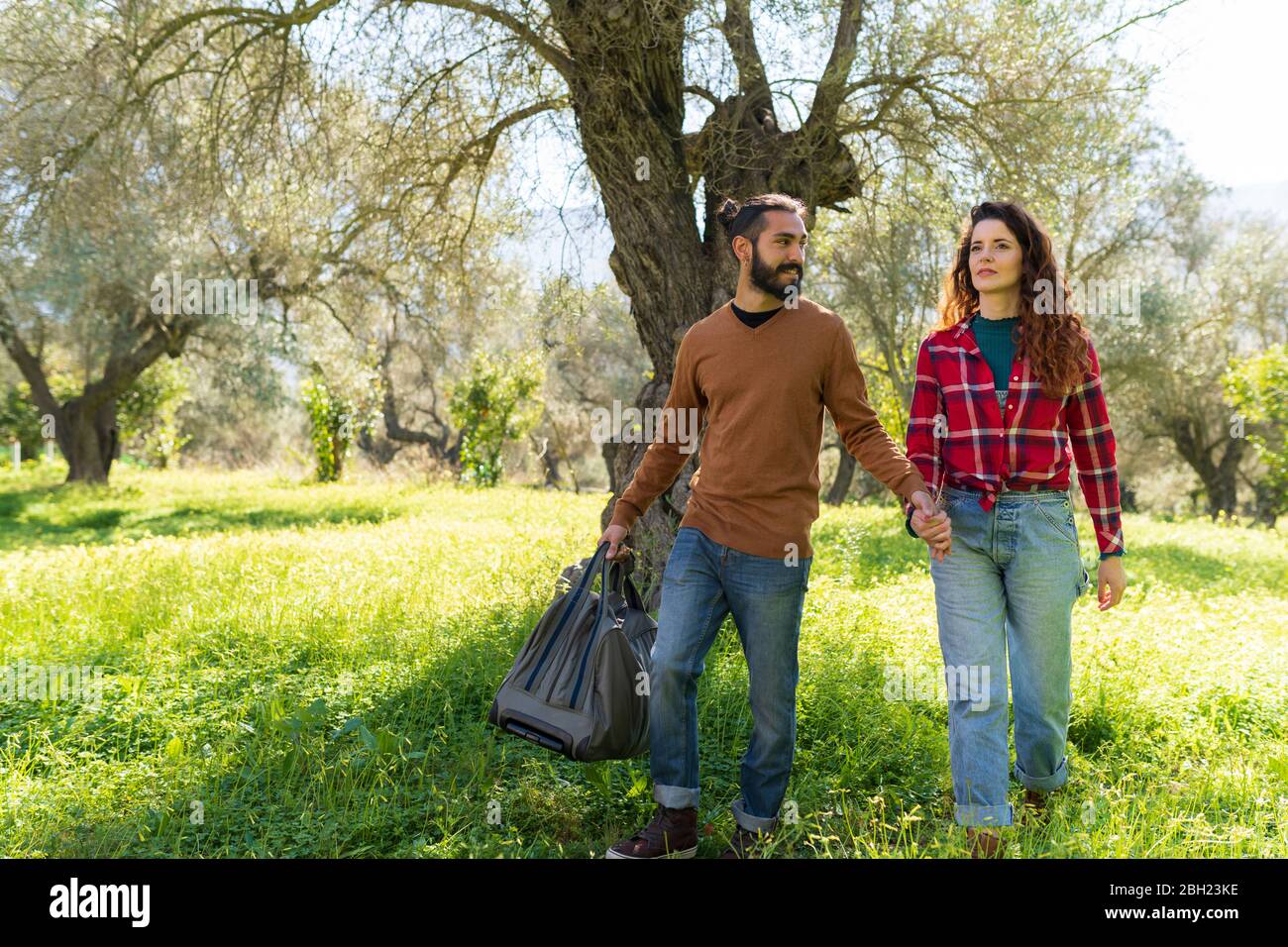 Couple avec sac de voyage main dans la main dans la campagne Banque D'Images