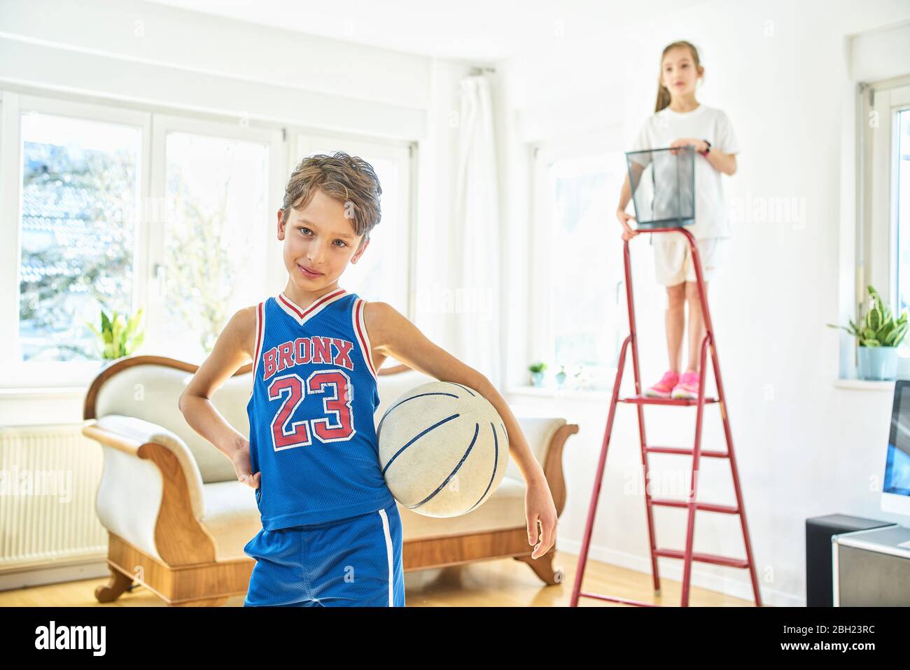 Portrait d'un garçon et d'une fille jouant au basket-ball dans la salle de séjour Banque D'Images