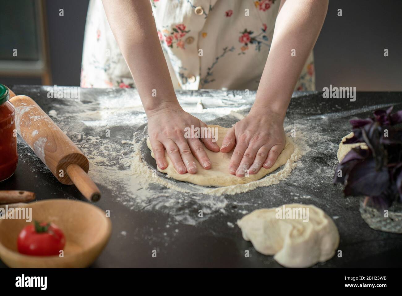 Les mains de la femme pétrient la pâte sur le plan de travail Banque D'Images