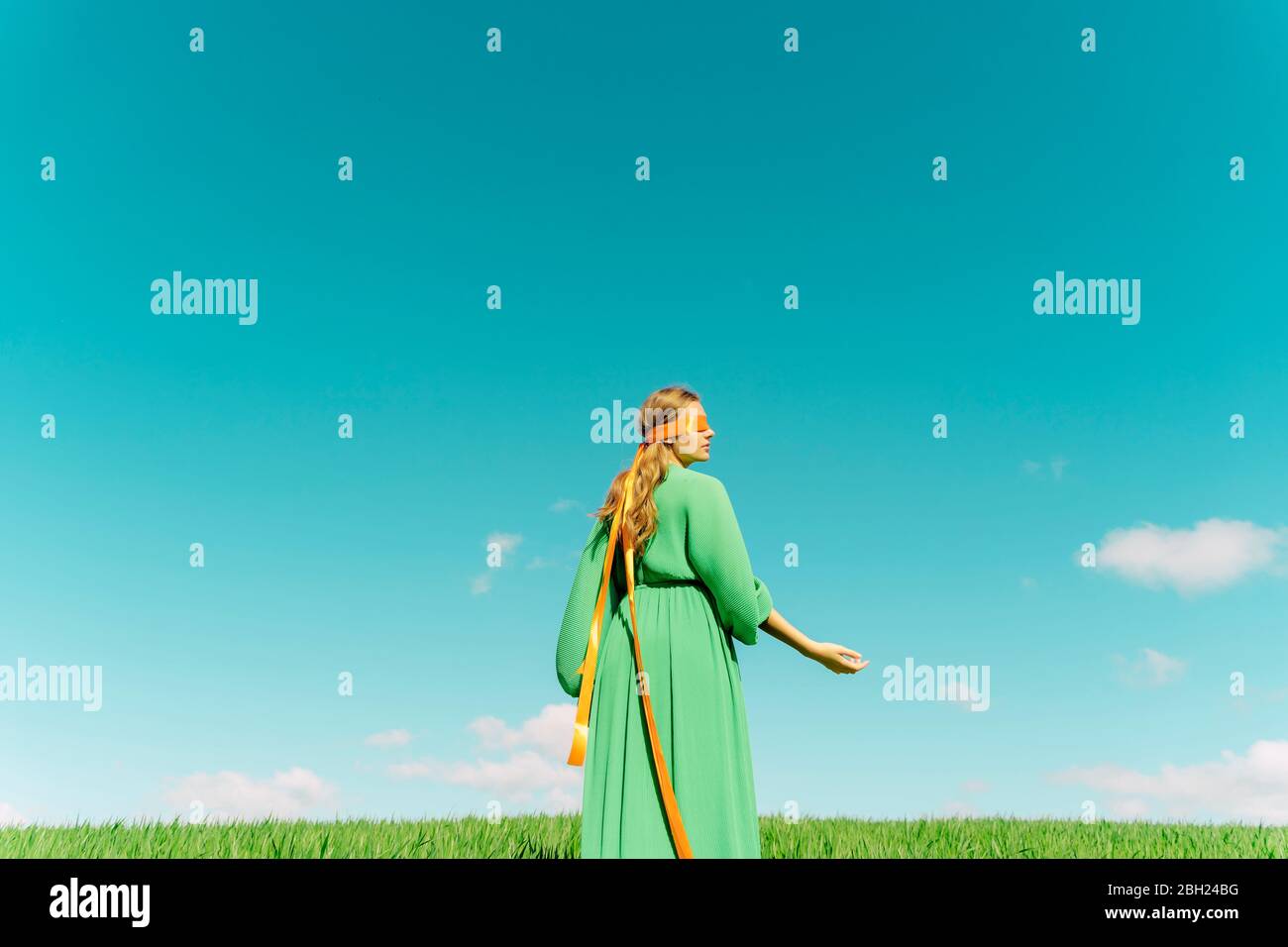 Une jeune femme aux yeux bandés portant une robe verte debout dans un champ Banque D'Images