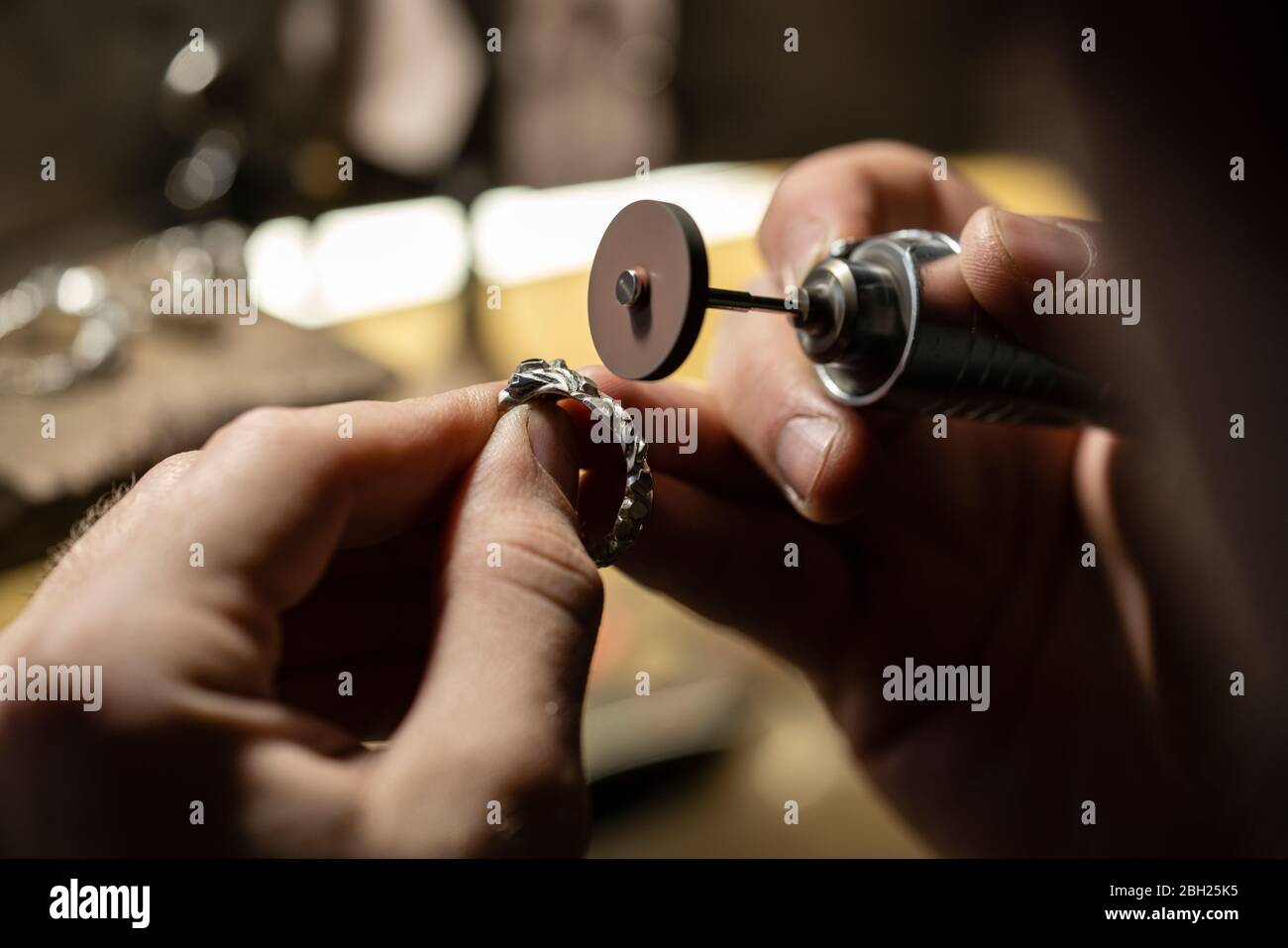 Gros plan d'une main de forgeron d'or meulant une bague d'argent Banque D'Images