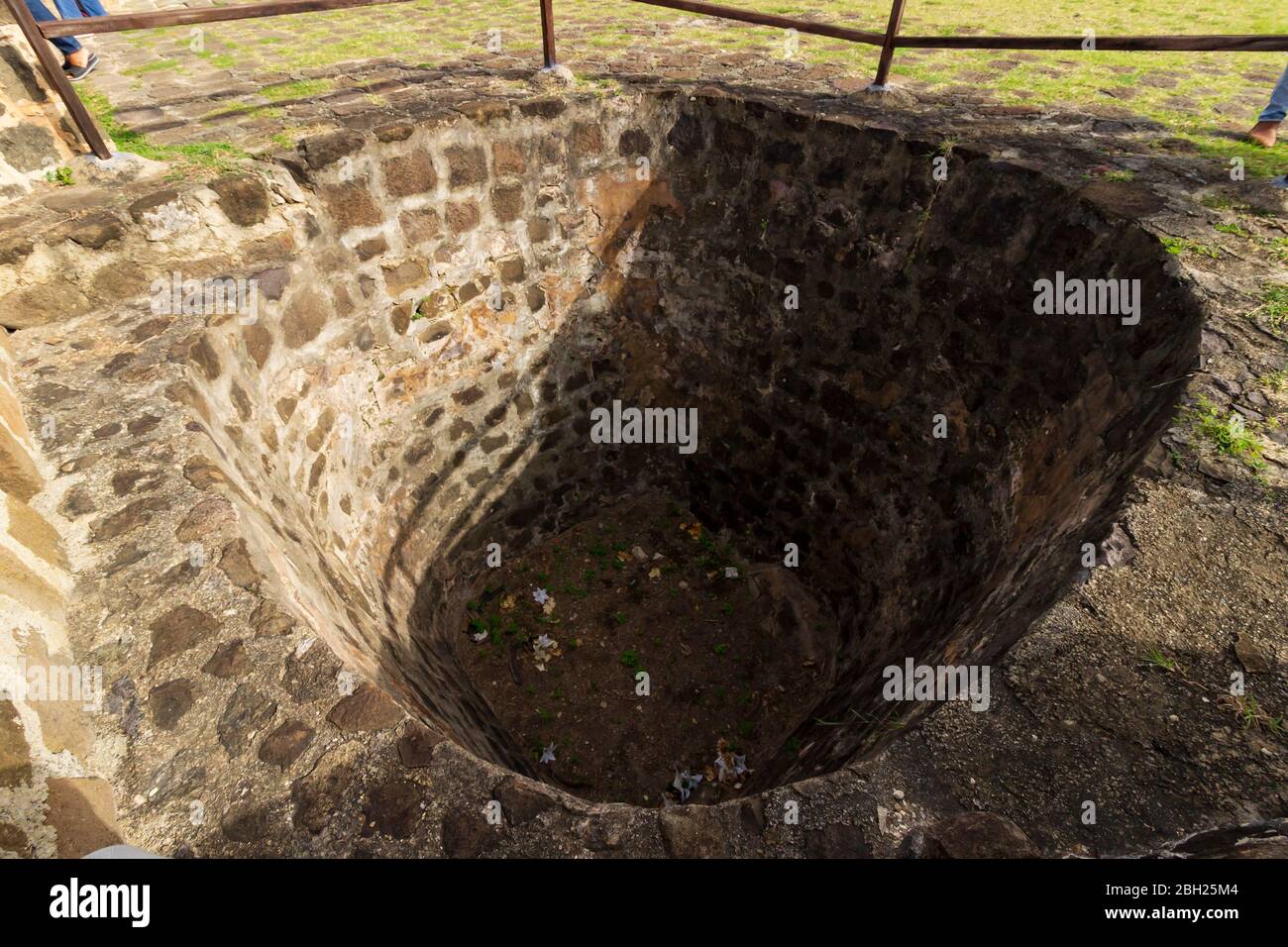 Un trou ou une fosse à fort Rodney datant de l'époque coloniale avec des côtés et la base couverts en maçonnerie de pierre et le dessus entouré d'une barrière de rampe en bois Banque D'Images