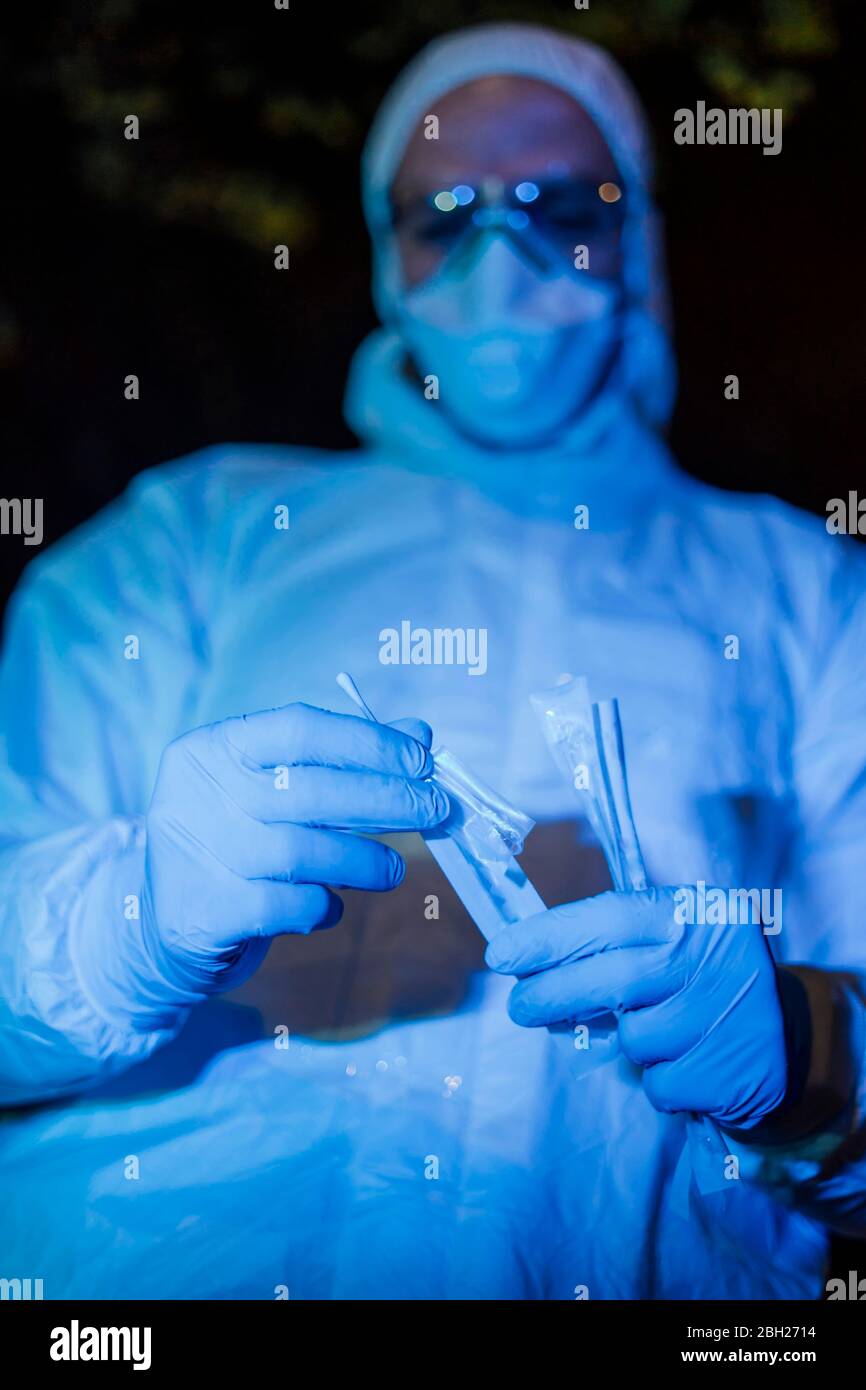 Médecin portant des vêtements de protection, tenant un test d'écouvillon viral Banque D'Images