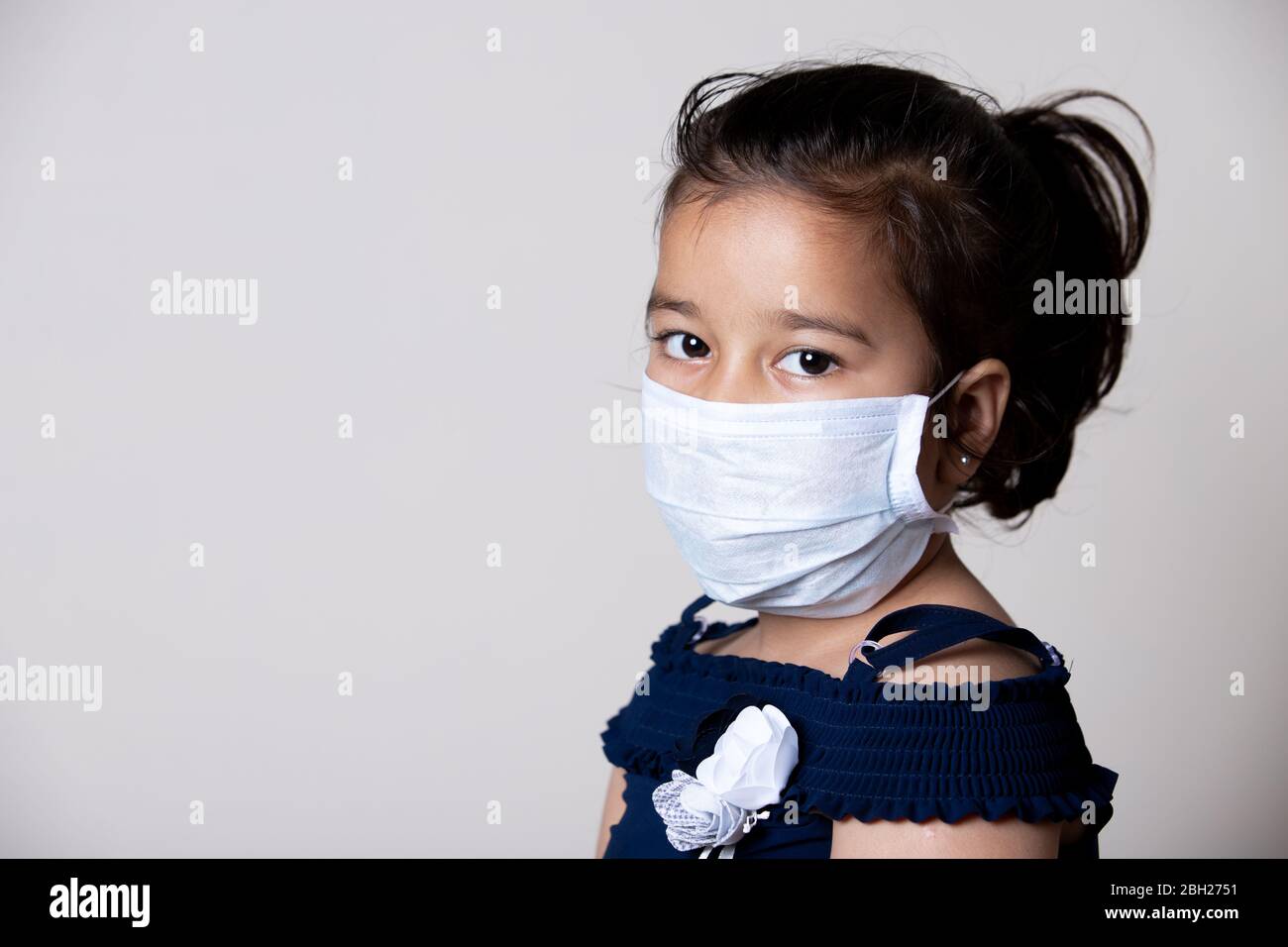 Visage de fille enfant couvert avec masque à la maison pour empêcher la propagation de l'infection du virus de Corona. Banque D'Images