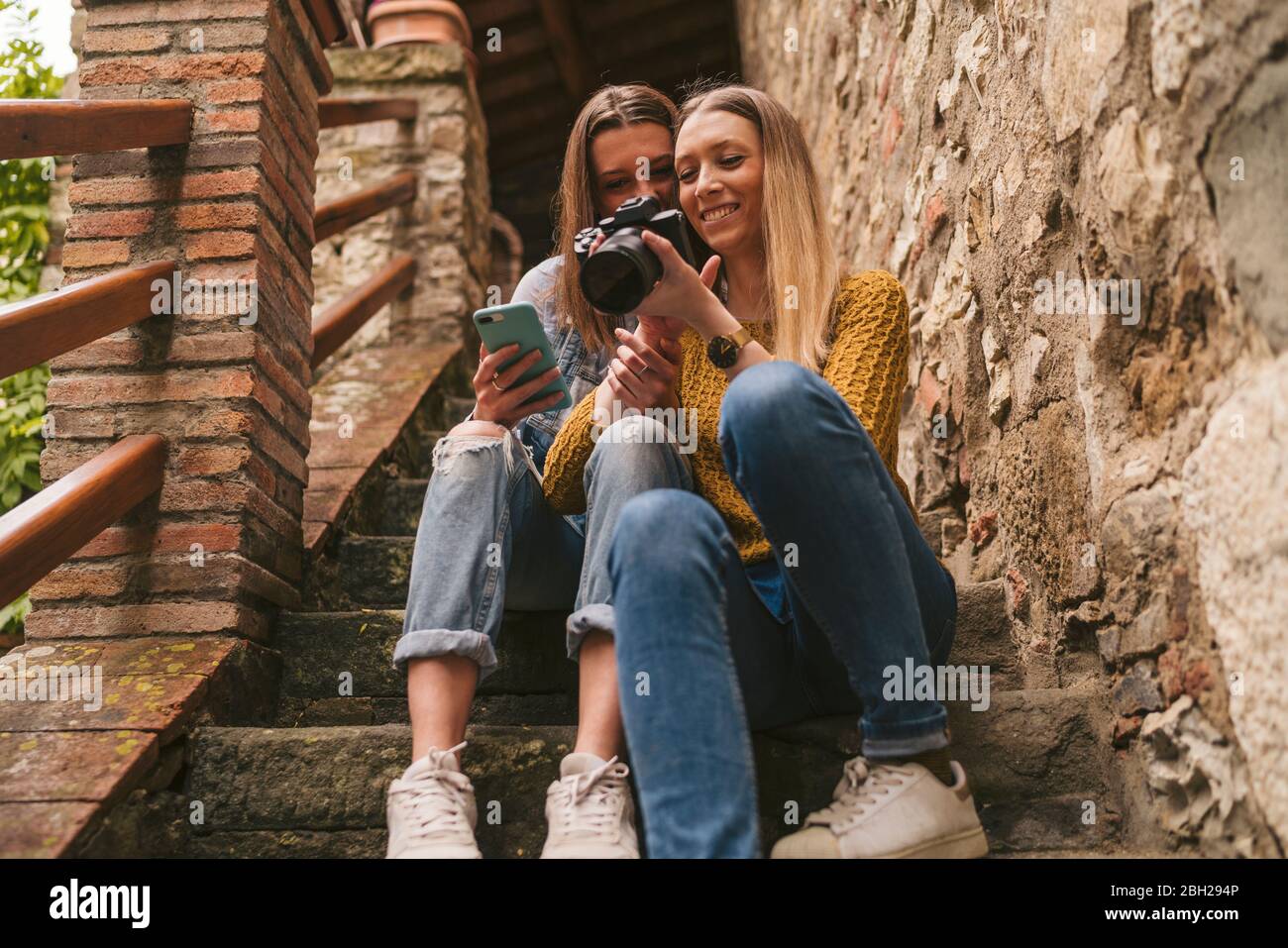 Deux jeunes femmes assises dans les escaliers, regardant la caméra, Greve in Chianti, Toscane, Italie Banque D'Images