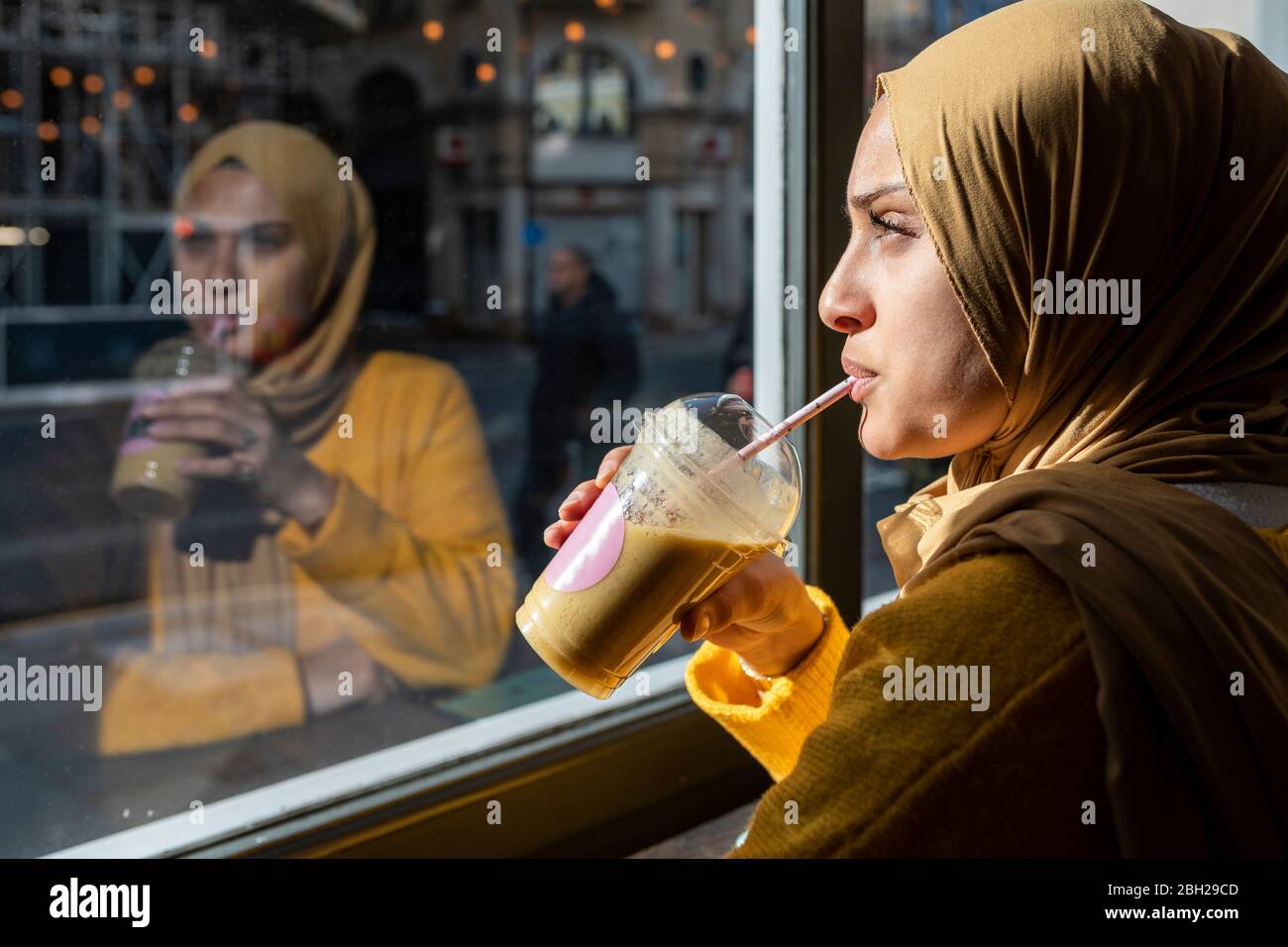 Portrait de la jeune femme pensive qui boit du smoothie dans un café Banque D'Images