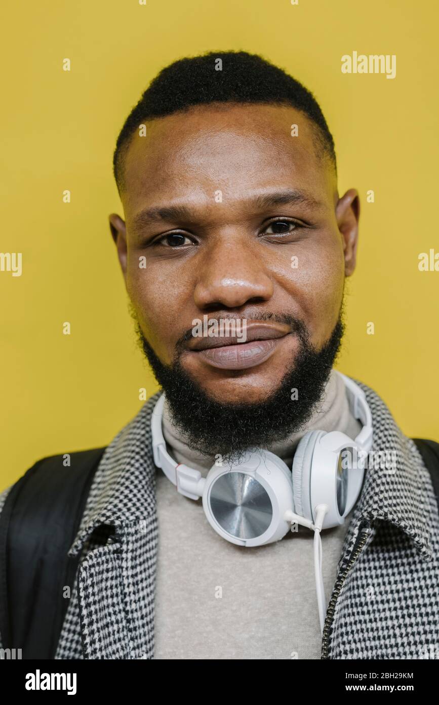 Portrait d'un homme élégant avec casque en police de mur jaune Banque D'Images