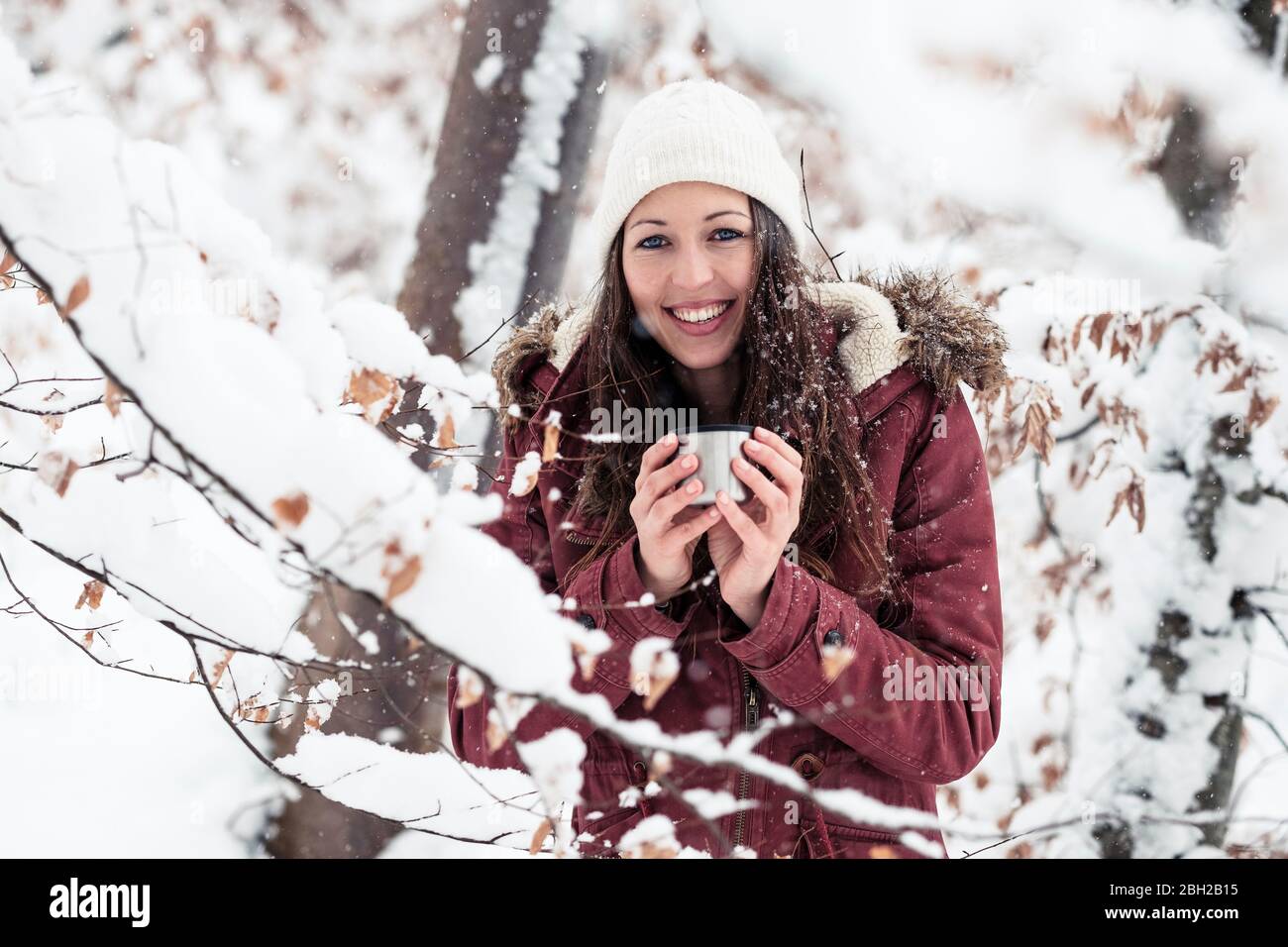 Portrait d'une jeune femme heureuse avec une boisson chaude en hiver Banque D'Images
