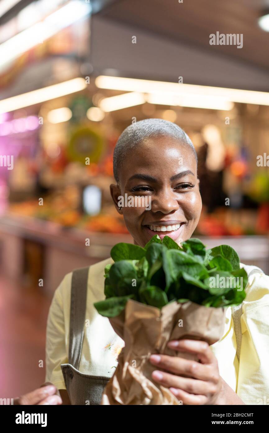 Portrait d'une femme heureuse tenant un sac en papier dans un hall de marché Banque D'Images