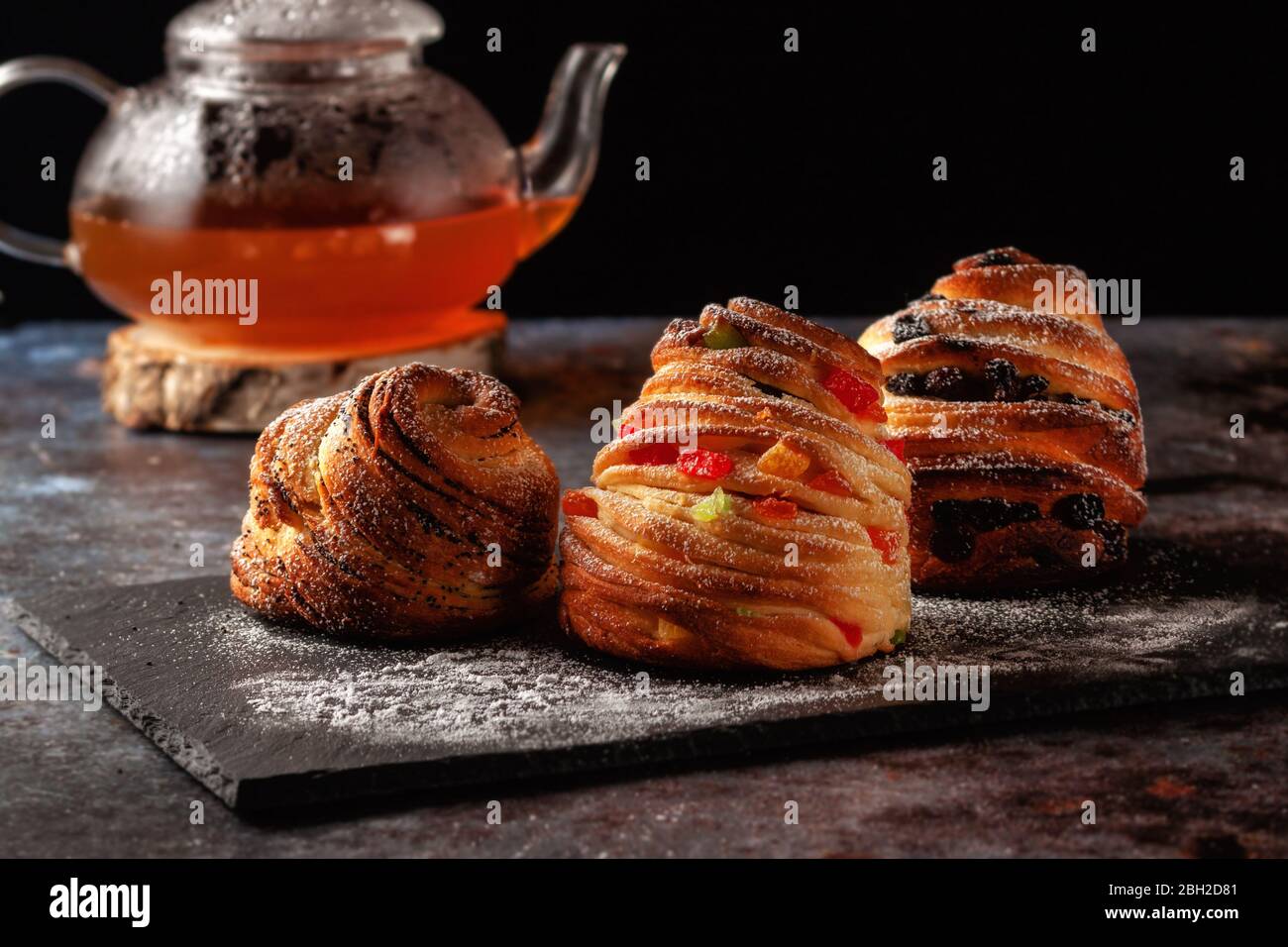 Kraffins aux raisins secs, fruits confits et graines de pavot, arrosés de sucre en poudre. Banque D'Images