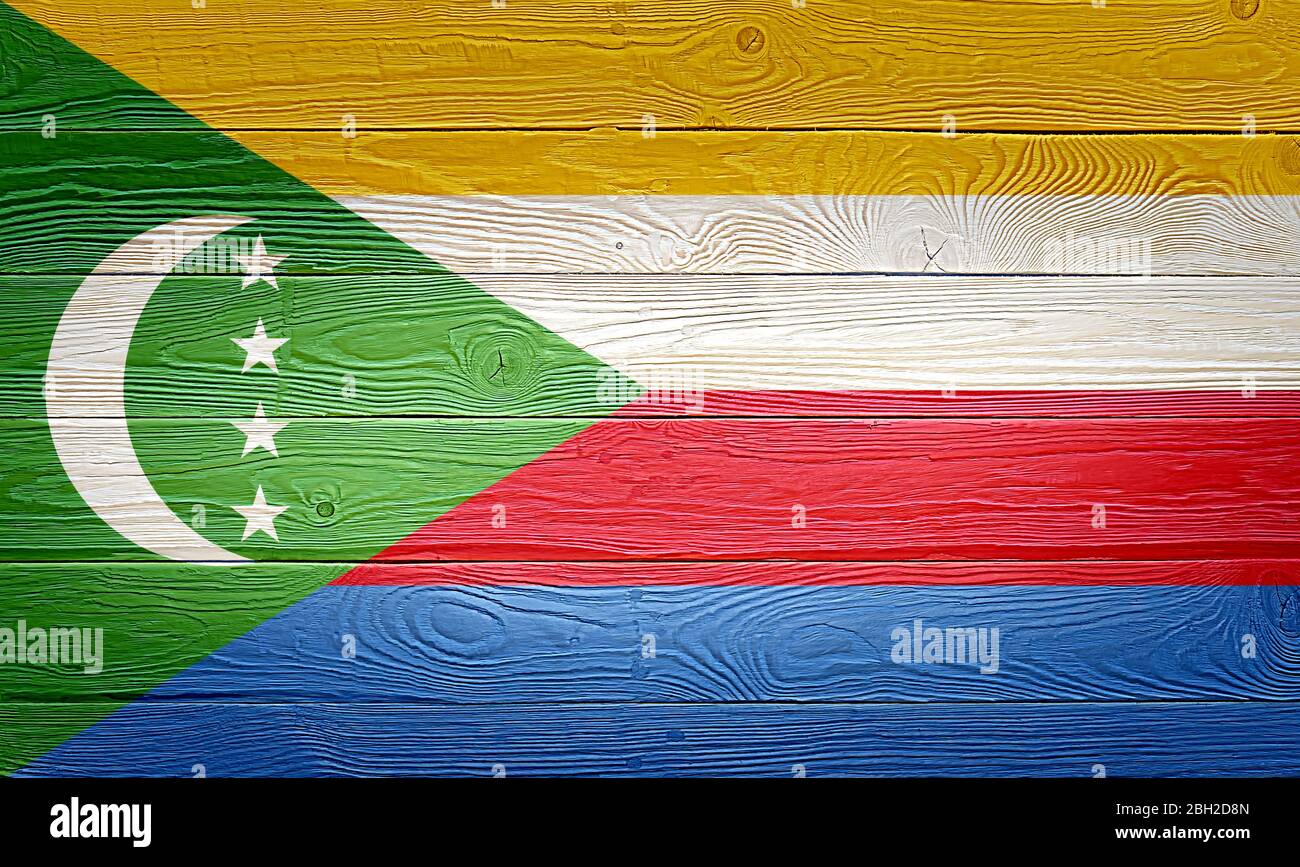 Drapeau des Comores peint sur fond de planche de bois ancien. Texture de planche en bois à noeuds et lumière naturelle brossée. Texture en bois fond drapeau des Comores. Banque D'Images