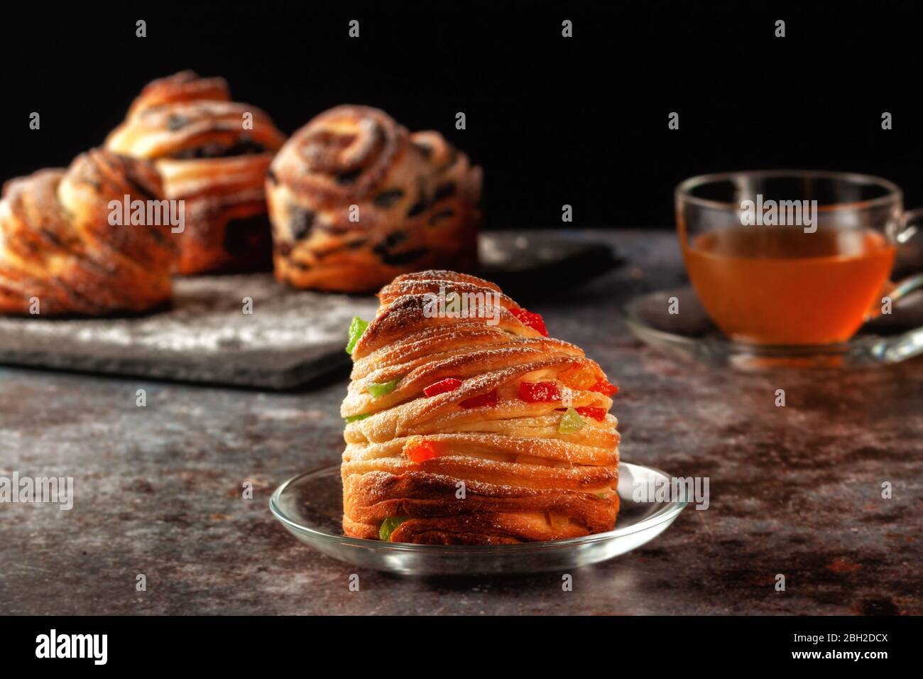 Kraffins aux raisins secs, fruits confits et graines de pavot, arrosés de sucre en poudre. Banque D'Images