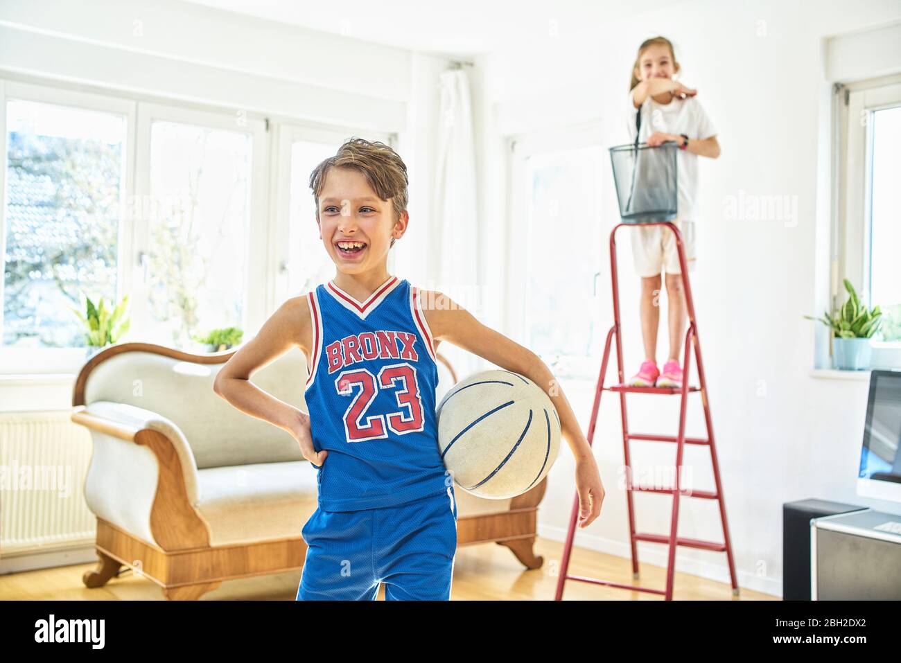 Un garçon et une fille heureux jouant au basket-ball dans le salon Banque D'Images